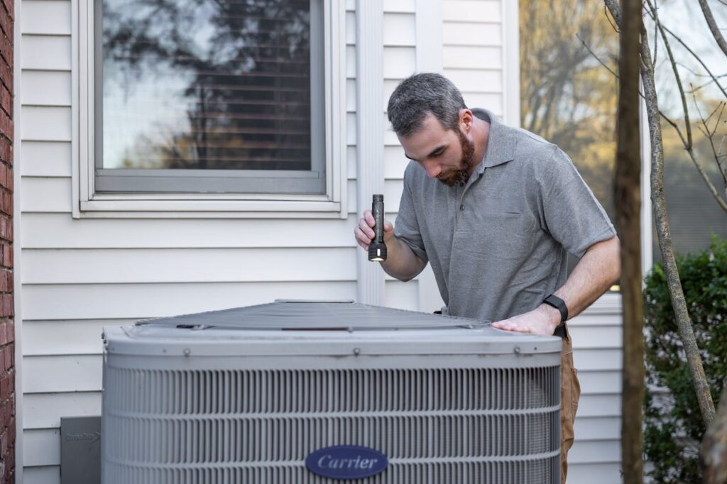 A technician inspects an outdoor HVAC unit for maintenance.