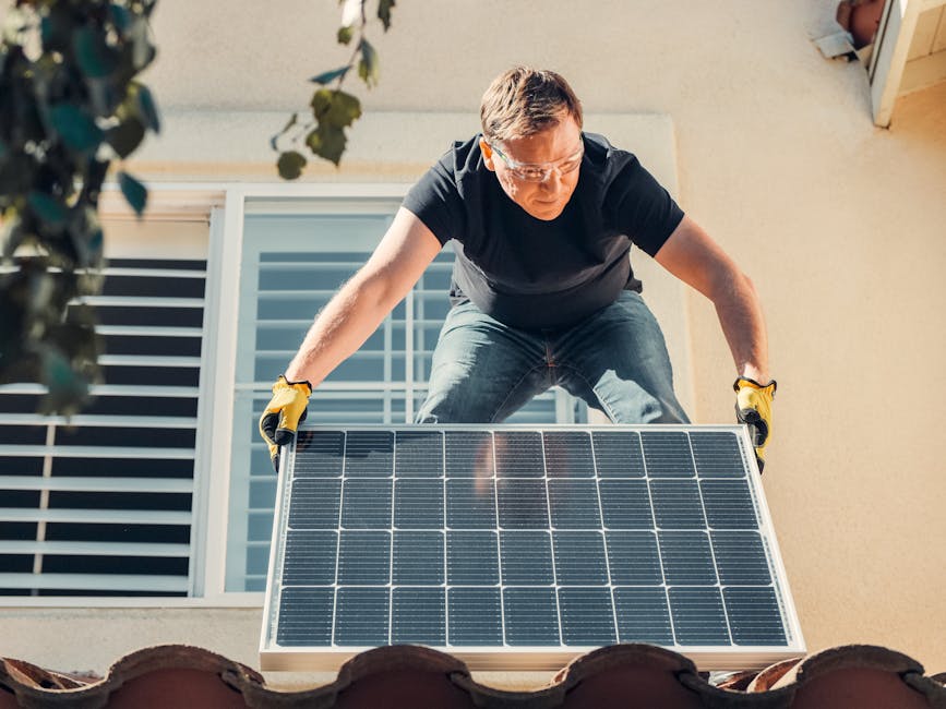 A man in safety glasses installs a solar panel on a house roof, promoting renewable energy.